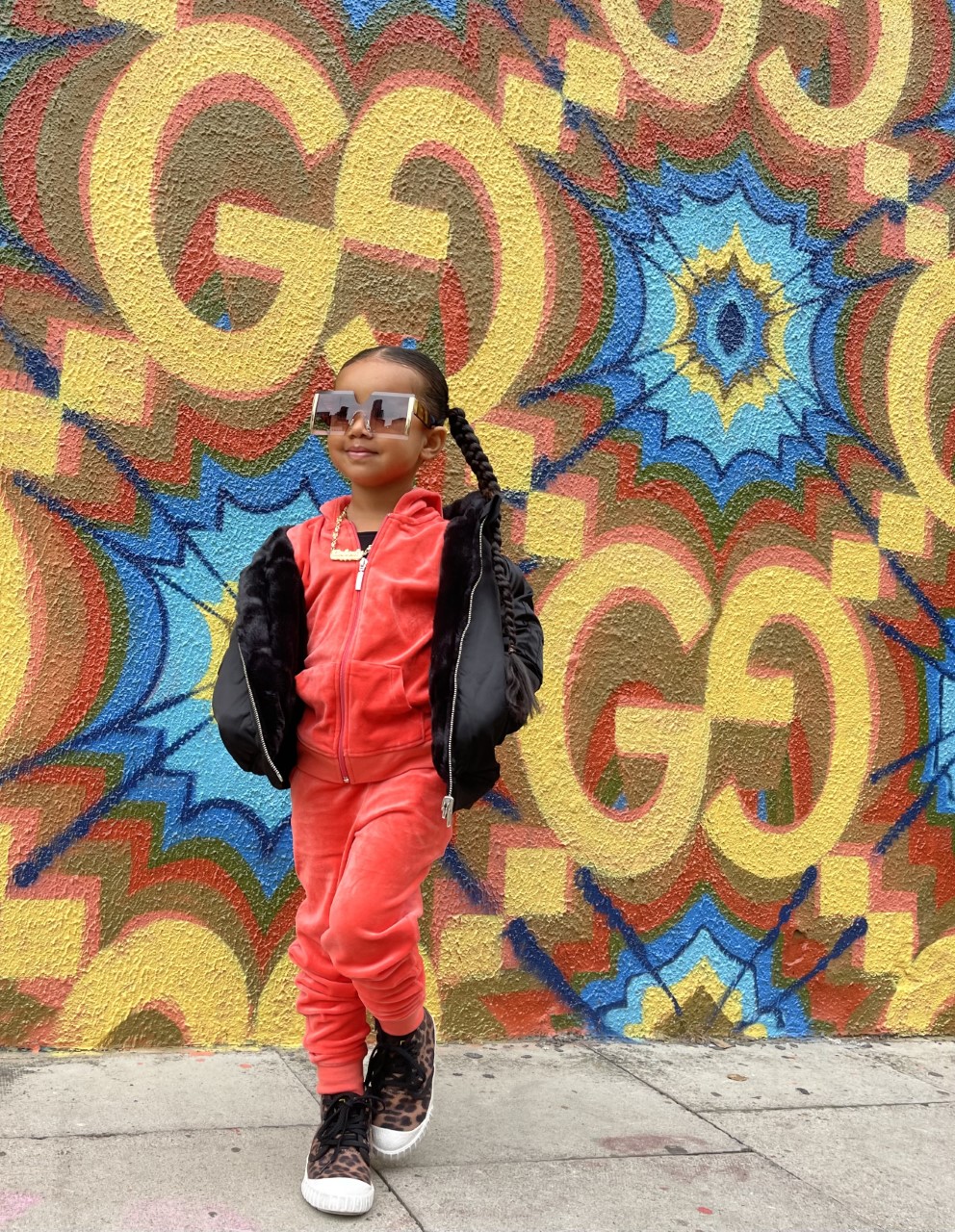 We took this photo at the Gucci store in London. Kimberly is vearing an orange set with a fluffy black reversible jacket and leopard printed shoes. 